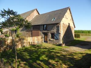 una antigua casa de piedra con una valla de madera en Gîte à la ferme en pleine nature, en Pleine-Fougères