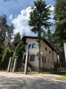 une maison blanche avec une clôture devant elle dans l'établissement Вила Пенчеви, кк. Цигов чарк, à Tsigov Chark