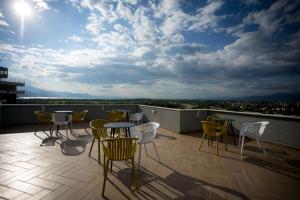 a patio with tables and chairs on a roof at Sky Hotel in Shkodër