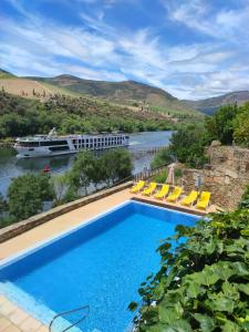 a swimming pool next to a river with a cruise ship at Hotel Casa do Tua in Foz Tua