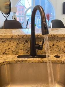 a kitchen sink with water running from a faucet at Downtown Baltimore Skyline Luxury Studio in Baltimore