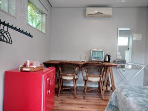 uma cozinha com uma mesa com cadeiras e uma televisão em Hospedaria Shaolin Suite na Lagoa da Conceição em Florianópolis