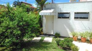 una casa blanca con una puerta y algunas plantas en Hospedaria Shaolin Suite na Lagoa da Conceição en Florianópolis