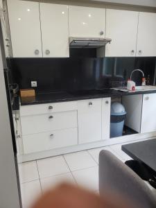 a kitchen with white cabinets and a black counter top at Appartement meublé aux portes de Genève in Annemasse