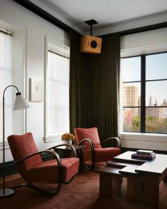 a living room with chairs and a table and windows at Nine Orchard in New York
