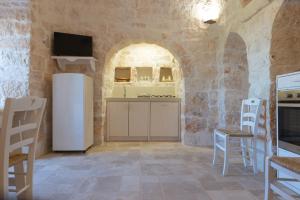 a kitchen with a refrigerator and chairs in a room at Il nido delle rondini in Cisternino