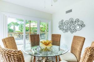a dining room with a glass table and chairs at You can't get closer to the beach than this beachy 3 bedroom condo in Siesta Key +31 photos