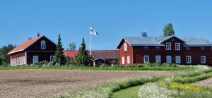 Lemettilä Countryside Accommodation في Petäjävesi: حظيرة حمراء كبيرة ومنزل وميدان