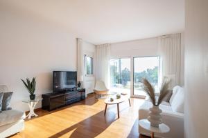 een woonkamer met een bank en een tv bij Grand Panoramic Villa Lagonissi in Lagonissi