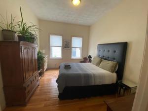 um quarto com uma cama, uma cómoda e janelas em Egleston Square Condo Jamaica Plain em Boston