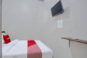 1 dormitorio con 1 cama y TV en la pared en OYO 3439 Wisma Tri Handayani Syariah en Bandar Lampung