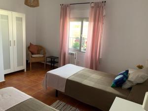 a bedroom with two beds and a chair and a window at La Casa de Sally- Vèlez Blanco in Vélez Blanco +24 photos