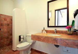 a bathroom with a toilet, sink and mirror at Hotel Rancho Encantado in Bacalar