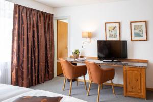 a hotel room with a desk with a television and chairs at Cristallo Arosa Hotel in Arosa