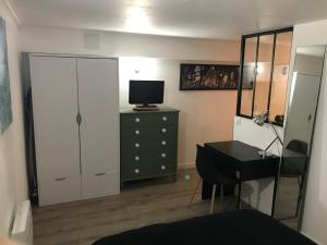 um quarto com uma secretária e uma cómoda com uma televisão em Joli Studio/T1 Rennes em Rennes