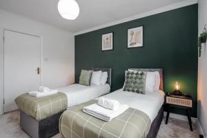 two beds in a room with a green wall at Large Penthouse by Damask Homes with Parking in Redbridge