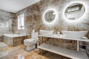 a bathroom with two sinks and a toilet at Large Penthouse by Damask Homes with Parking in Redbridge