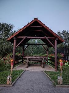 un pabellón de madera con un banco en un jardín en House Mesić, en Smoljanac