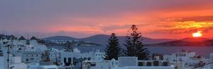 einen Sonnenuntergang über einer Stadt mit Bergen im Hintergrund in der Unterkunft Dimele in Mykonos Stadt