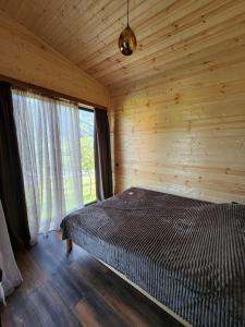 Ce lit se trouve dans une chambre en bois dotée d'une fenêtre. dans l'établissement Georgian exotic cottages, 