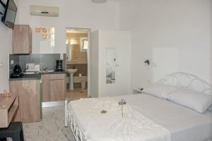 a bedroom with a large white bed and a kitchen at Petros Giatras - Rooms in Zakynthos Town