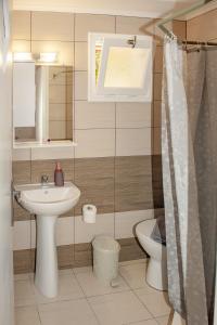 a bathroom with a sink and a toilet and a window at Petros Giatras - Rooms in Zakynthos