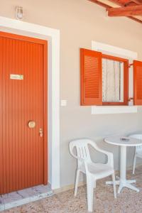 uma porta vermelha num quarto com uma mesa e cadeiras em Petros Giatras - Rooms em Zakynthos