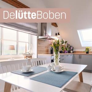 a kitchen with a white table with a vase of flowers at De lütte Boben in Dollerup