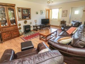 a living room with leather couches and a table at Drovers Rest in Otterburn