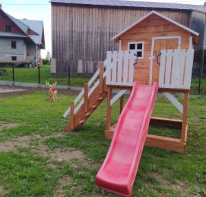 a playground with a slide and two white chairs at Domki pod Grapą in Trybsz