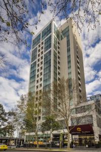 un grand bâtiment avec un arbre devant lui dans l'établissement Clarion Suites Gateway, à Melbourne