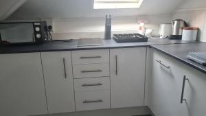 cocina con armarios blancos y encimera negra en Montague House Apartments, en Llandudno