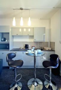 a kitchen with a table and two bar stools at Montague House Apartments in Llandudno