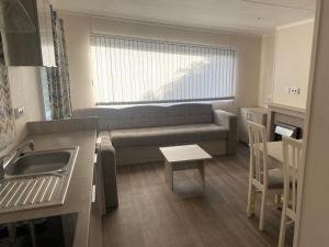 ein kleines Wohnzimmer mit einem Sofa und einer Küche in der Unterkunft Mooi verblijf op rustig park in Ermelo