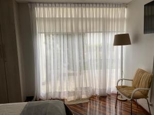 a bedroom with a bed and a window with a chair at Habitaciones en San Isidro in Lima