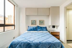 a bedroom with a blue bed and a window at Fabulous studio in the heart of Medellín in Medellín