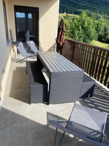 a balcony with a bench and an umbrella and chairs at Appartement Le Grand Duc in Gérardmer