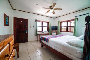 - une chambre avec un lit et un ventilateur de plafond dans l'établissement Splash Inn Dive Resort & Villas, à West End