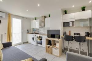 a kitchen with white cabinets and a living room at Appartement Gare St Charles Vieux Port in Marseille