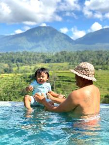 a man and a child sitting in the water at Pondok Nyoman in Bedugul