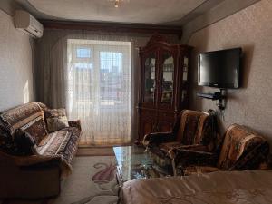 a living room with two chairs and a tv at Apartment near Airport and station Charbakh in Yerevan