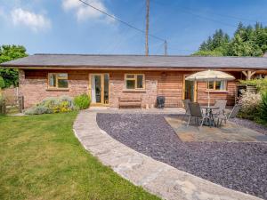 een huisje met een tafel en stoelen ervoor bij The Stable Rose Cottage in Yorkley