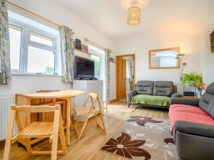 uma sala de estar com uma mesa e um sofá em The Stable Rose Cottage em Yorkley
