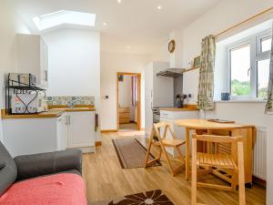 een keuken en een woonkamer met een tafel in een kamer bij The Stable Rose Cottage in Yorkley