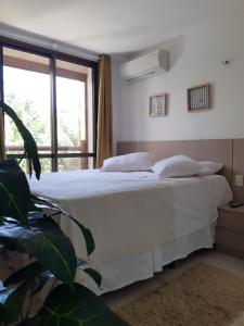 ein Schlafzimmer mit einem Bett mit weißer Bettwäsche und einem Fenster in der Unterkunft Apartamento Waiwai Cumbuco in Cumbuco + 40 Fotos