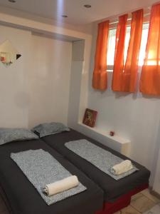 two beds in a bedroom with orange curtains at Stadion in Belgrade