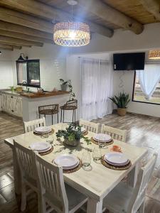 Casa de campo liquidambar في سان بيدرو: طاولة طعام مع أطباق وكراسي بيضاء