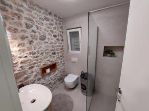 a bathroom with a toilet and a glass shower at Apartman Zlatan in Drniš +25 photos