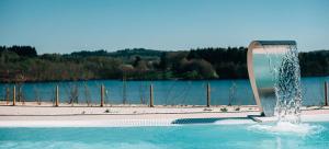una fuente en una piscina junto a un cuerpo de agua en Lumineuse maison neuve, cosy,67m², 2 Chambres/6 couchages 1km Lac, 200m du bourg. Vue paisible, sur la nature en Saint-Pardoux