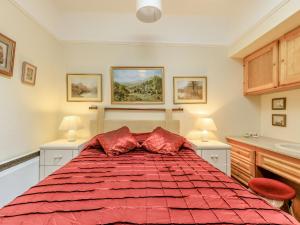 una camera da letto con un grande letto rosso con due lampade di Clooneavin Apartment 5 a Lynmouth